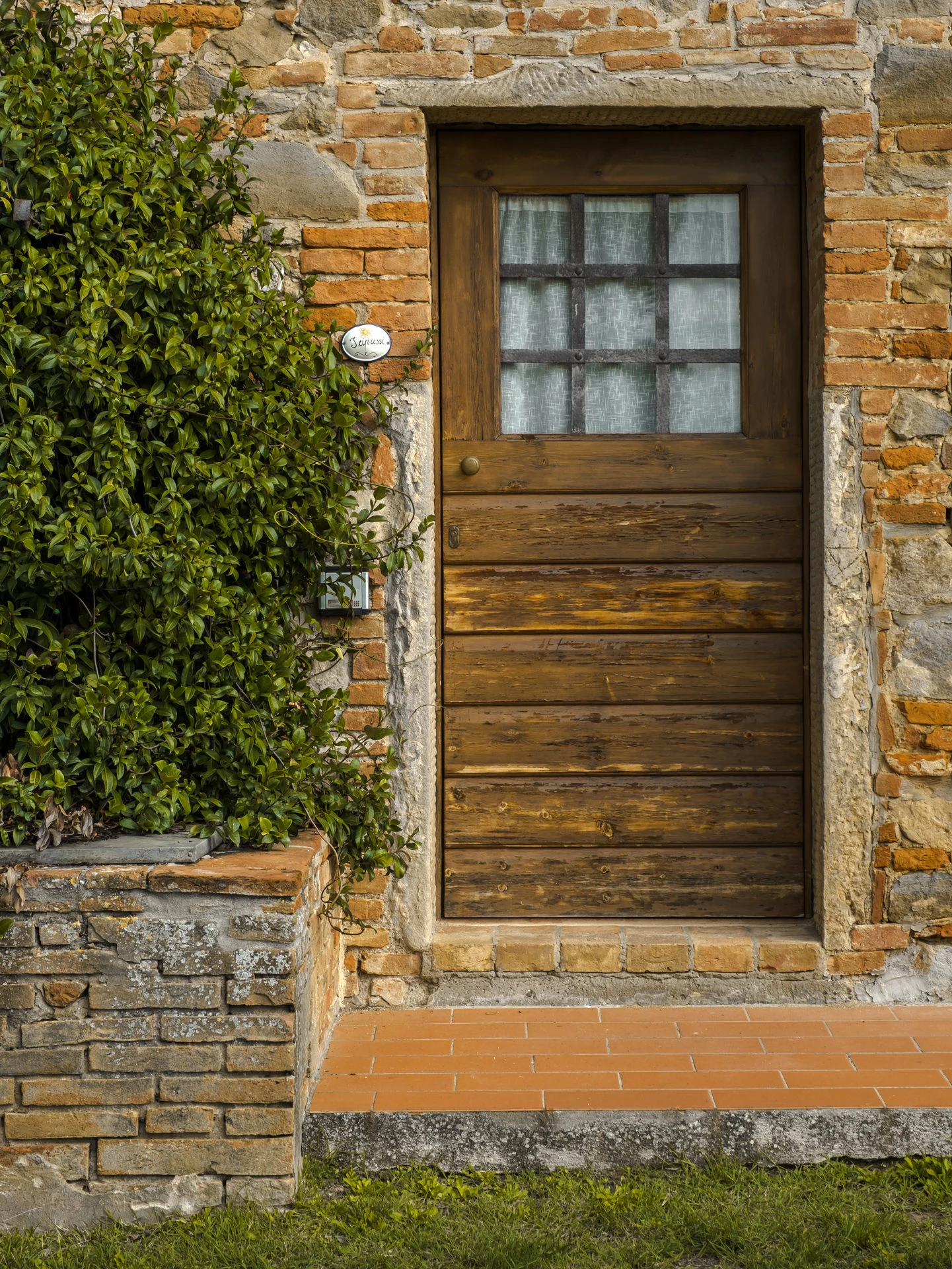 Fotografie per un agriturismo in Toscana: Fattoria di Colleoli 7 Portone in legno e muro in mattoni di un agriturismo in Toscana
