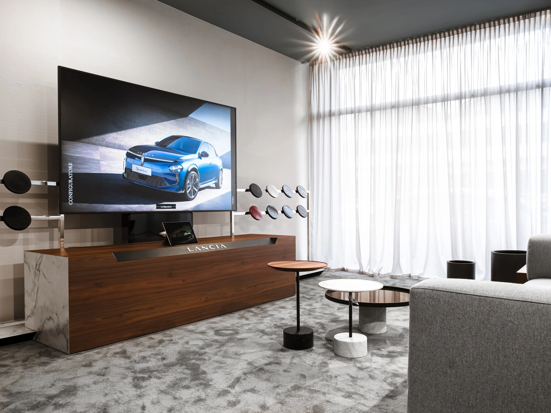 Showroom con auto esposta su pedana e salotto d'attesa