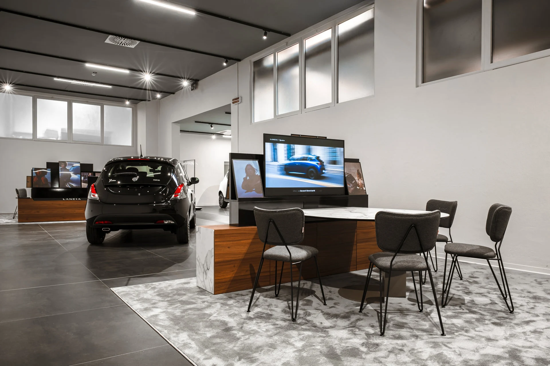 Interno di una concessionaria con auto esposte e postazioni di lavoro