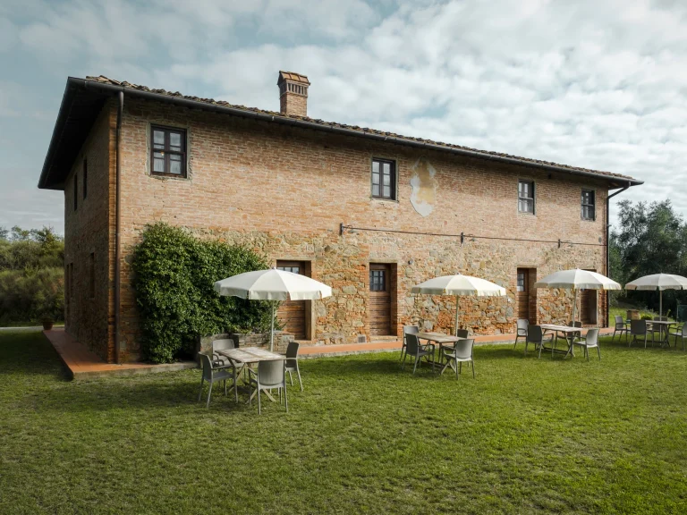 Casale in pietra con giardino e ombrelloni nella campagna toscana
