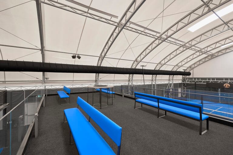 Fotografo di interni a Pistoia 4 Interno di un club di padel con campi coperti e panche blu a Montale