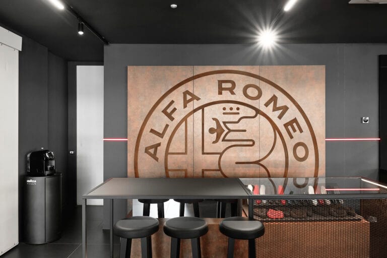 Area lounge dello showroom Alfa Romeo a Prato con logo a parete