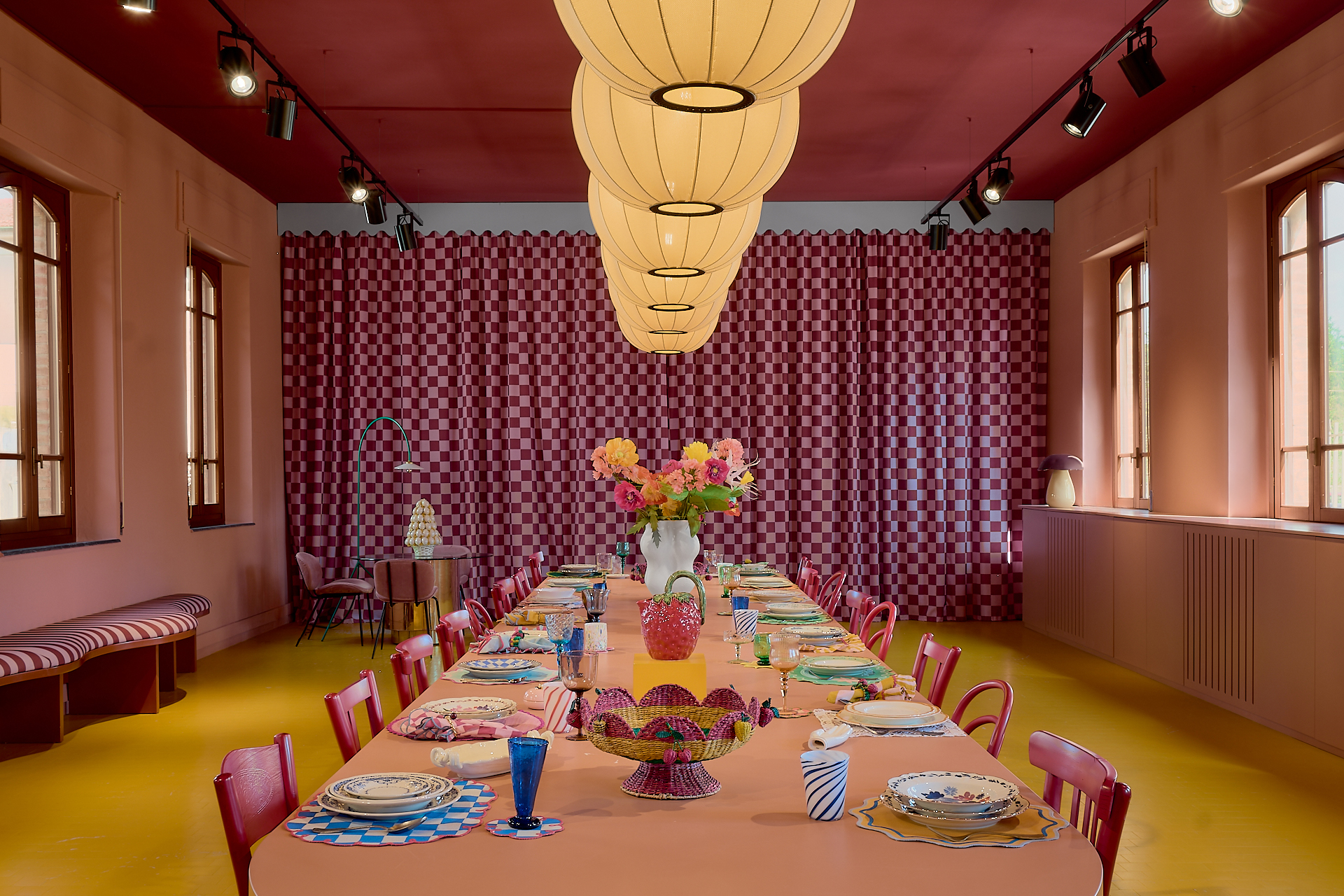 Sala da pranzo con lunga tavola apparecchiata, pareti rosse e lampadario