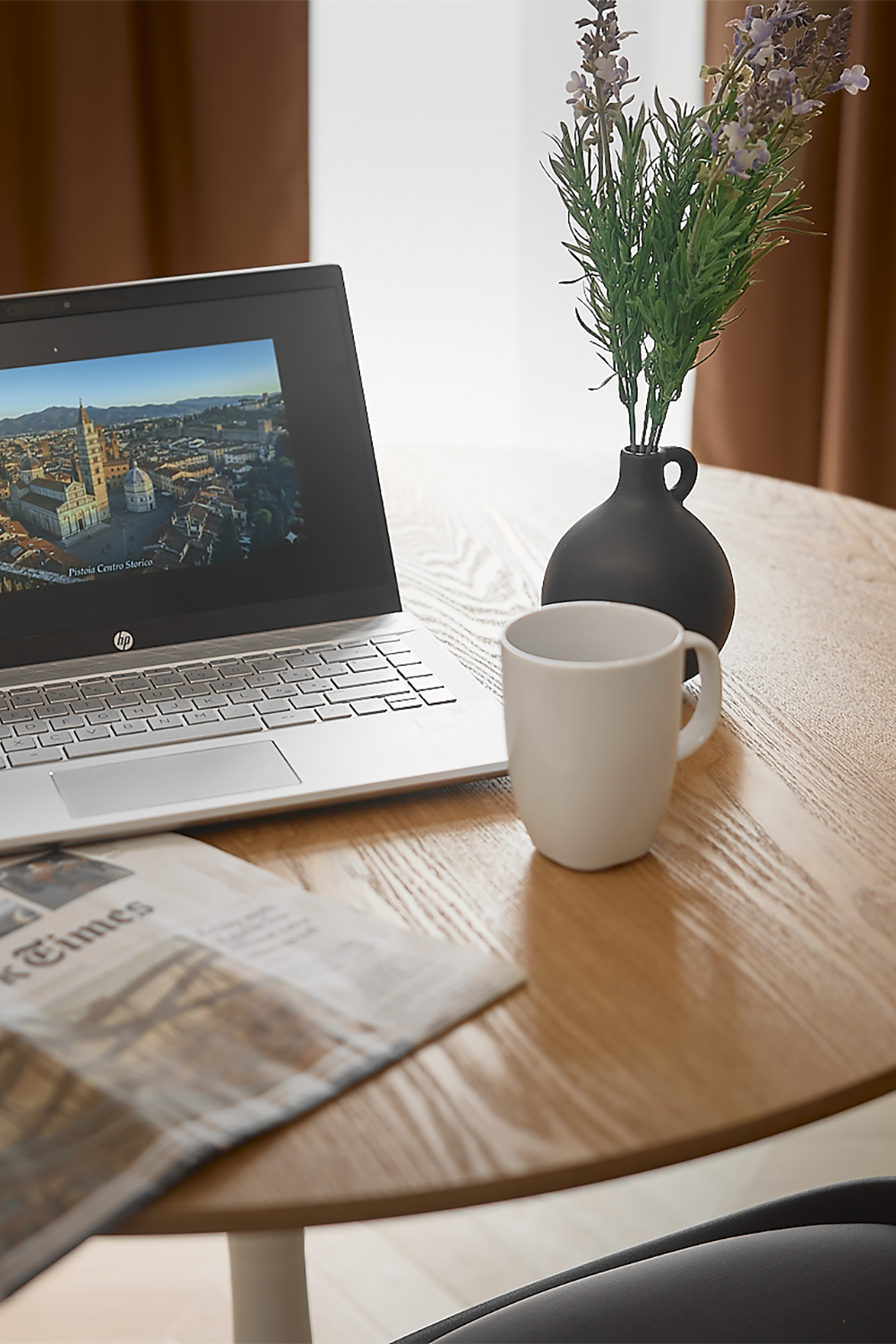 Dettaglio di una scrivania con computer portatile, tazza e pianta