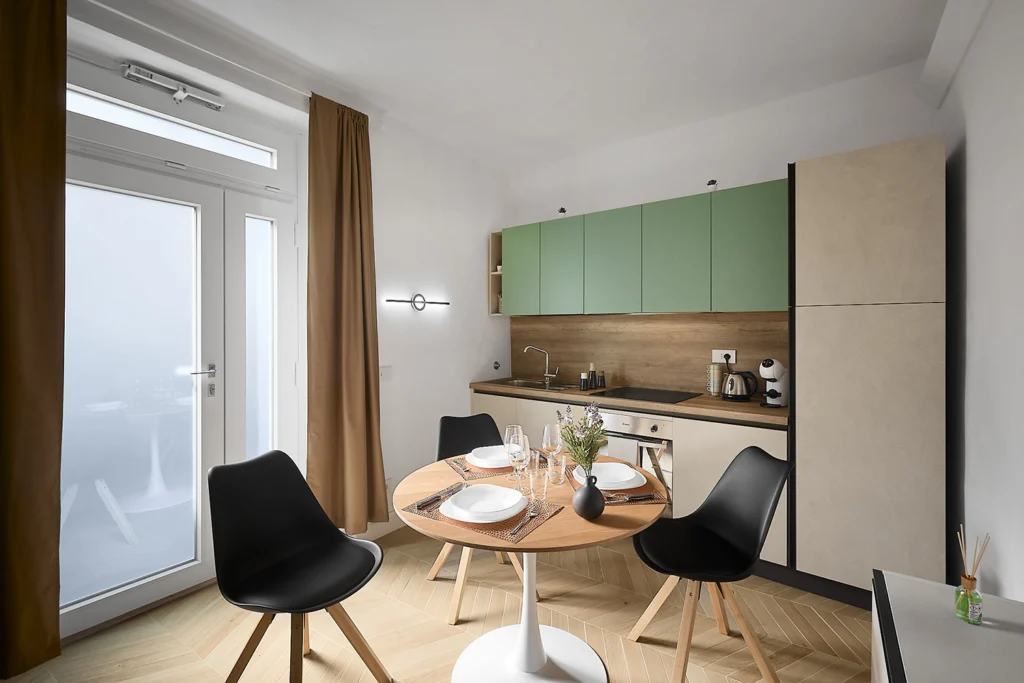 Cucina verde salvia con tavolo rotondo in un appartamento Airbnb a Pistoia