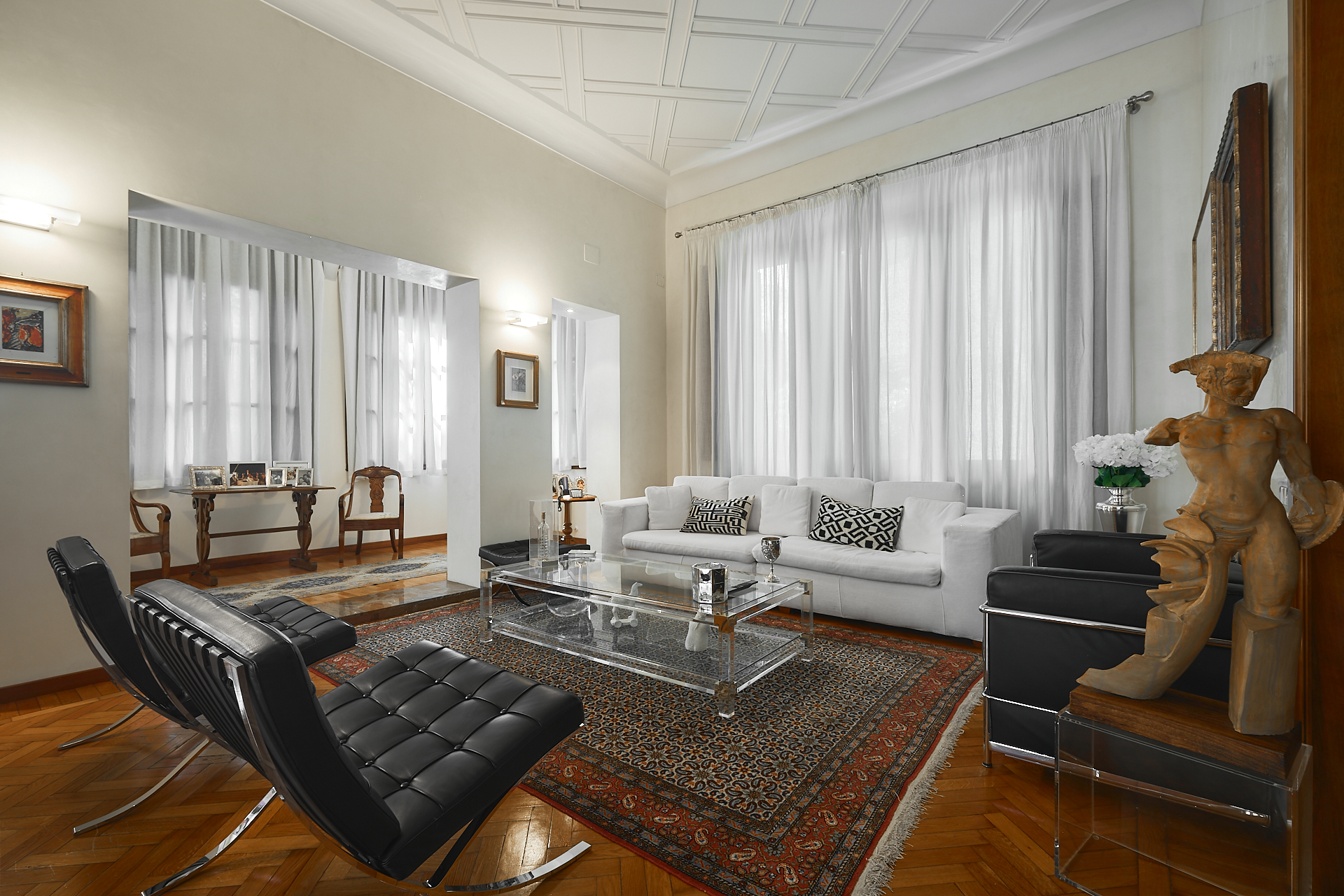 Soggiorno luminoso con poltrone in pelle nera e parquet a Prato